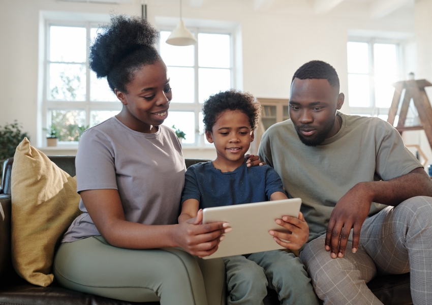 Contemporary young family of father, mother and son watching online movie